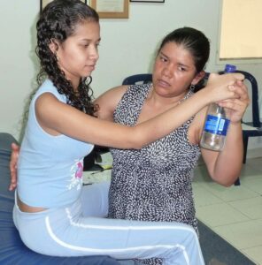 Medical professional helping Paula to hold a bottle a bottle of water